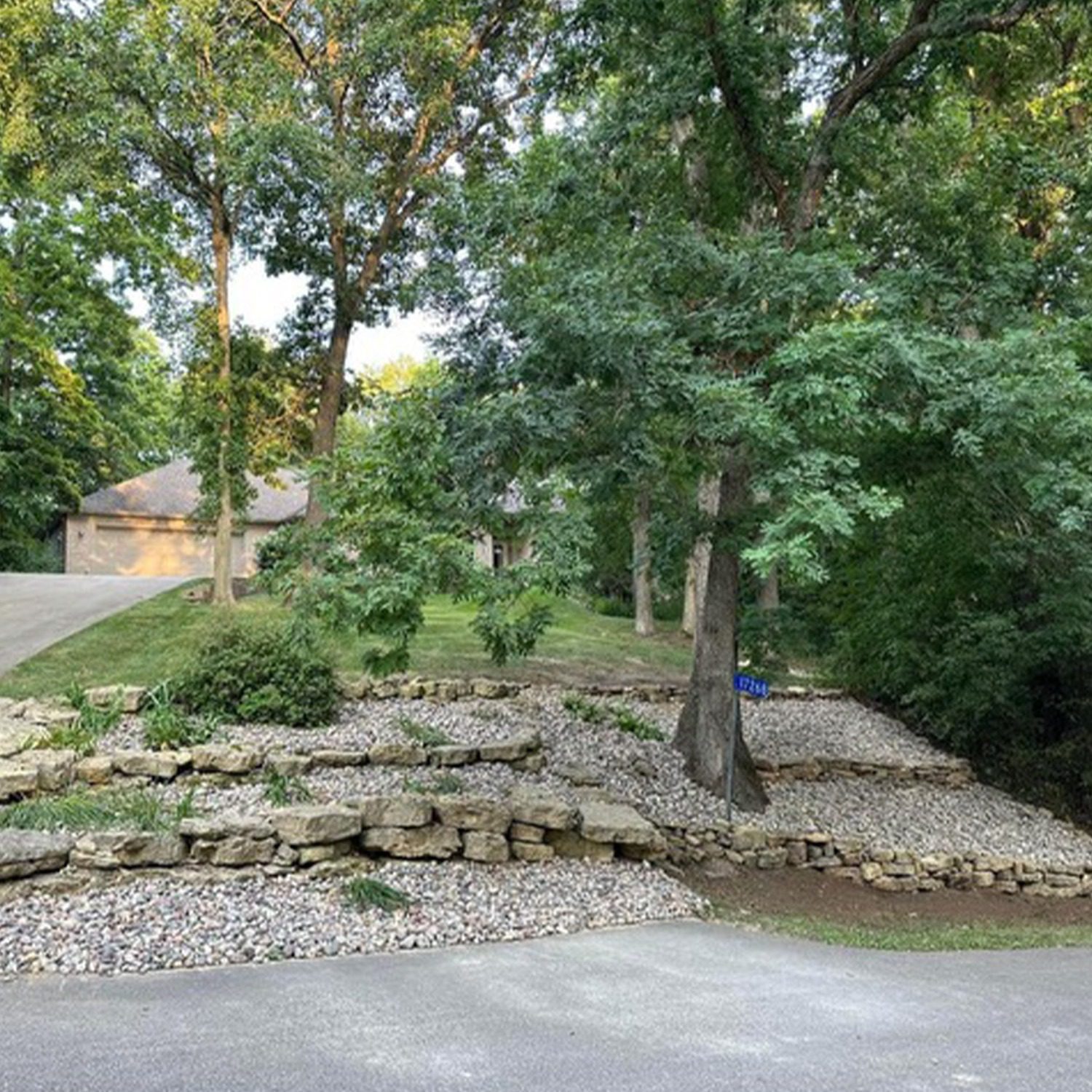 An image of a terraced landscaping project in a front yard with healthy plants, rock edging, and landscape rock.