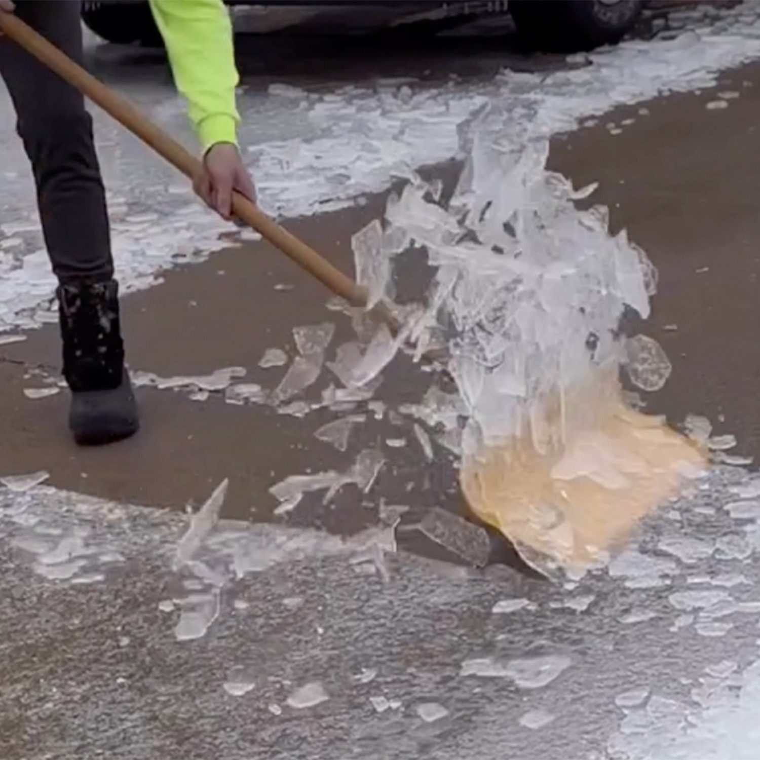 An image of a shovel breaking up ice on a driveway.