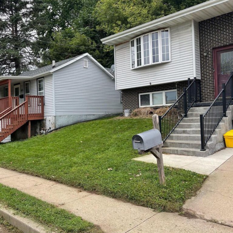 An after image of the lawn with the overgrowth removed and with freshly mowed grass, leaving the house unobstructed.