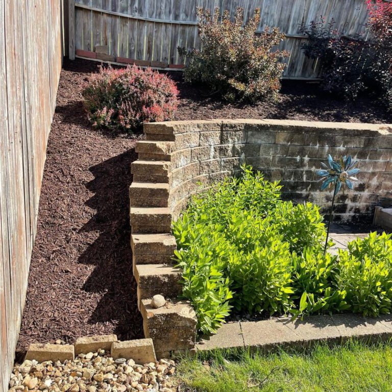 The after image of a landscaping project showing a tidy garden with mulch replacing the rock and with reinforced edges on the retention wall.