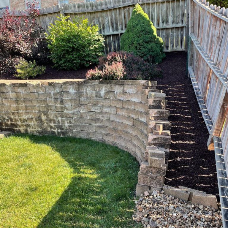 The after image of a landscaping project showing a tidy garden with mulch replacing the rock and with reinforced edges on the retention wall.