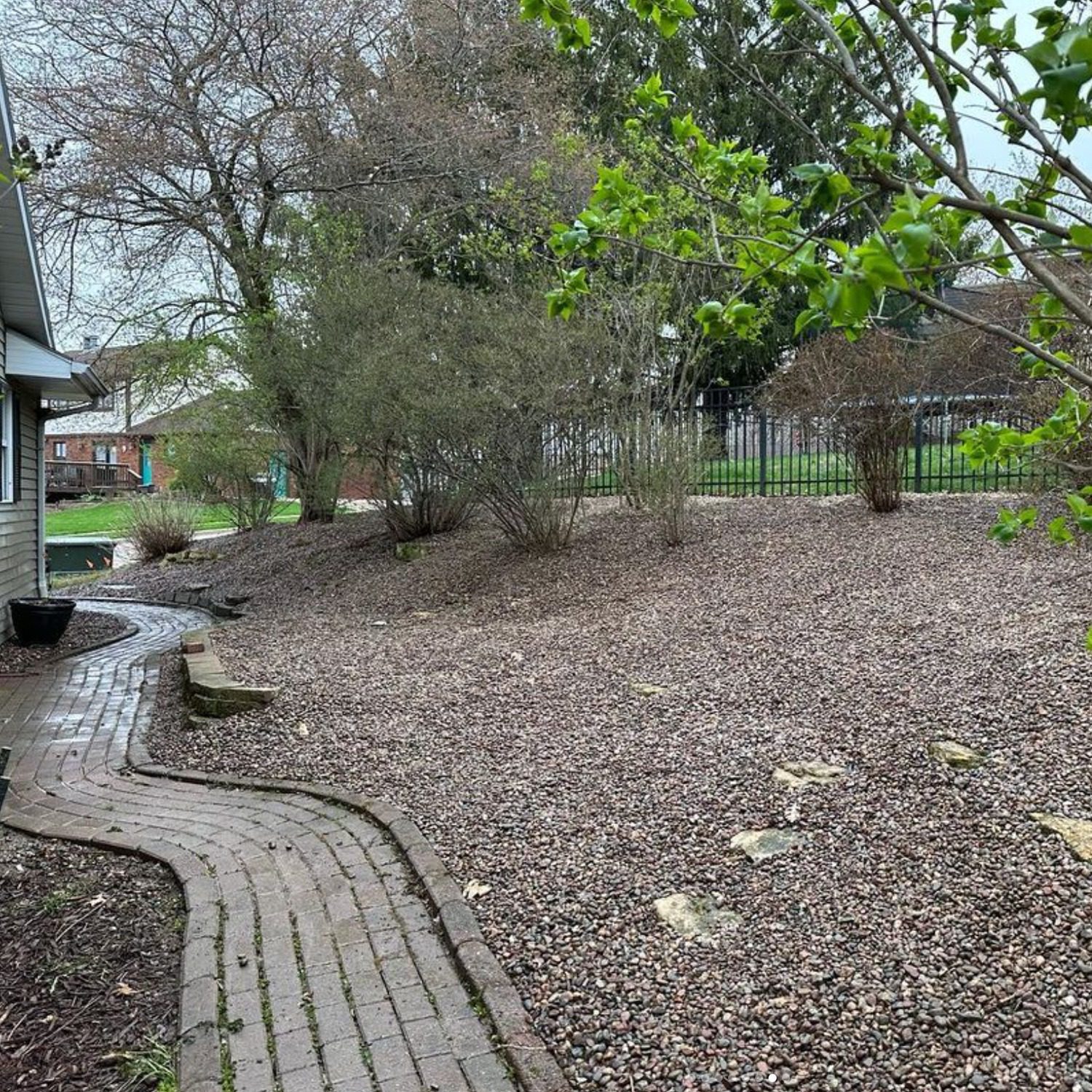 The after image of a yard clearing project showing the removal of leaves and yard debris, with the addition of landscaping rock in a now tidy environment.