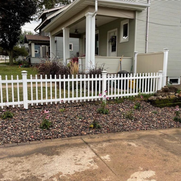 The after image of a landscaping project next to a driveway showing rock edging, landscaping rocks, and new plants.