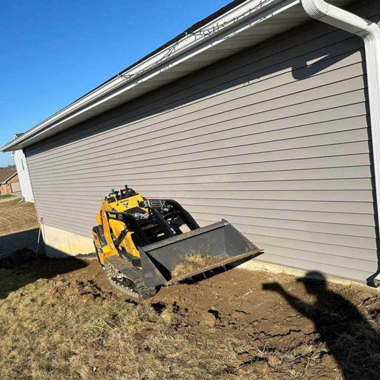 The before image of a landscaping project next to a house showing dirt and grass being removed.