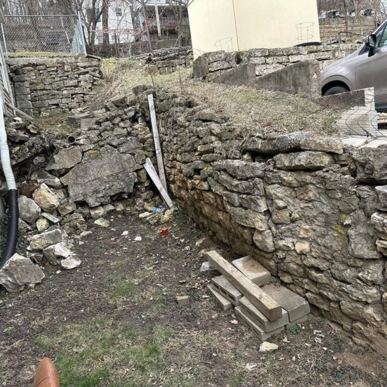 The before image of a retention wall, showcasing the old and falling apart retention wall that is to be replaced.