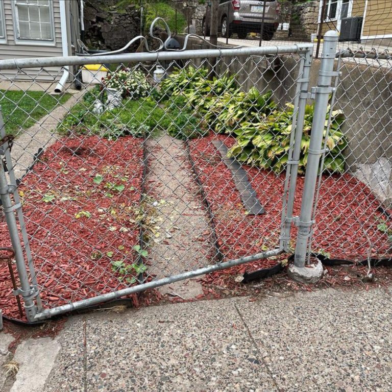 A before image of a lawn seeding project showing two strips of red mulch in a front yard.